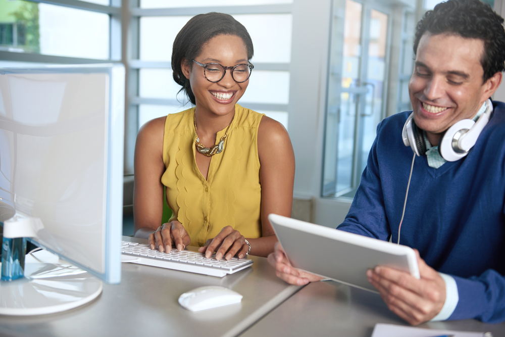 Two  colleages discussing ideas using a tablet and computer